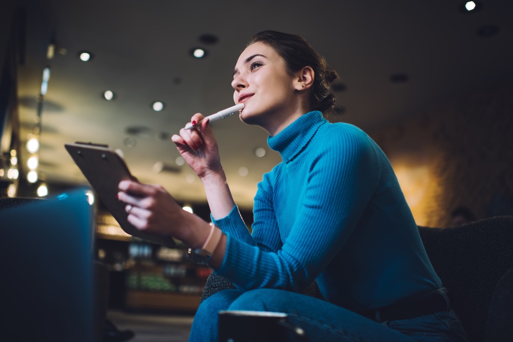 Thoughtful woman thinking on project From below of pensive female freelancer in blue wearing thinking on new project while sitting alone in cozy cafe and looking away